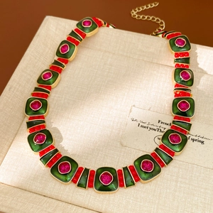 Macro view of vintage gold necklace with green gems and red beads on beige gift box
