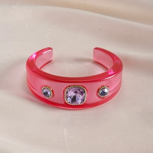 Detailed shot of pink resin cuff bracelet with purple crystals on warm velvet