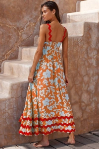 Detailed view of the wavy red trim and orange floral print on a summer maxi dress