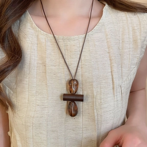 Detail of vintage amber resin pendant necklace with rustic cord on beige clothing
