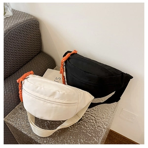 Detail view of canvas chest bags in black and cream white with orange drawstring accents