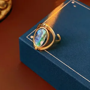Oval shell open ring in gold finish shown at 45-degree angle on a jewelry box