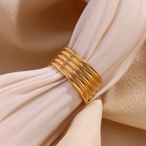 Vue macro d'une bague multicouche plaquée or 18 carats sur fond de soie beige douce
