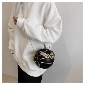 Detailed view of a black basketball-shaped crossbody bag with gold chain and white embroidery