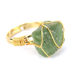 Macro detail of handmade wire-wrapped green raw stone ring with adjustable gold band