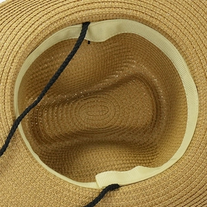 Detail of woven straw sun hat featuring an internal sweatband and adjustable black lanyard