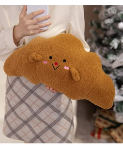 Close-up of soft plush croissant pillow with cute embroidered face in a cozy home setting