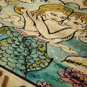 Macro view showing vintage bohemian textile texture with artistic angel and mermaid patterns
