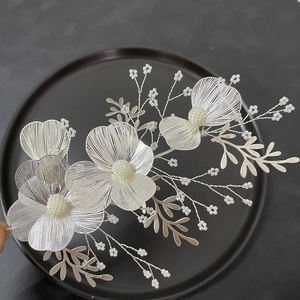 Macro detail of handmade silver floral hairpiece with woven wire and white pearls