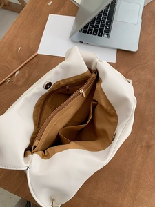 Internal view of white tote bag showing brown lining with zipper pocket and magnetic closure