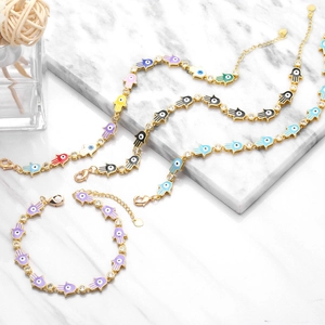Detail of Hamsa Hand bracelets with colorful enamel charms and crystals on gold chain