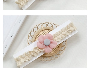 Detail of pink fabric flower headpiece with beige lace on a rustic woven coaster