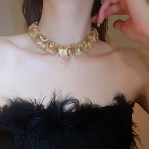 Close-up of luxury gold choker necklace featuring large square crystals on a model neck