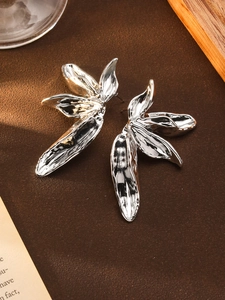 Macro shot of silver textured abstract floral earrings on a leather surface