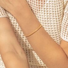 Close-up of a twisted gold rope bracelet worn on wrist showing detailed metal texture