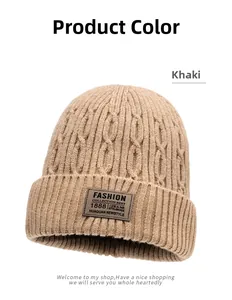 Detail of khaki cable knit texture and rectangular leather logo patch on thick winter beanie