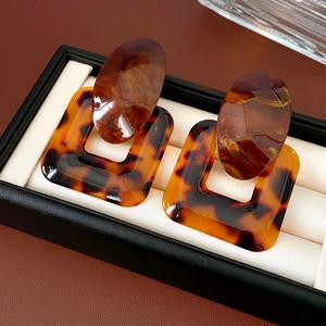 Macro shot of retro amber resin square and oval drop earrings in a black jewelry box