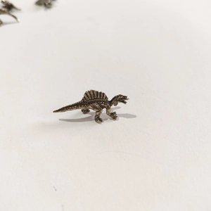 Macro view showing detailed skin texture and fin of a miniature brass Spinosaurus figurine