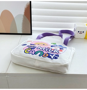 Close-up of white canvas tote bag with purple handles and cute cartoon girl graphics