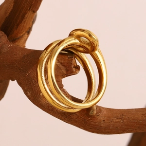 Detailed view of intertwined 18K gold plated knotted ring on natural wooden branch