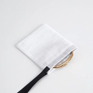 White cotton drawstring jewelry pouch shown with a gold rhinestone bracelet on white background