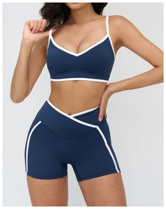Detail view of navy blue yoga set showing cross waist design and contrast white binding
