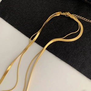 Close-up of golden double-layer necklace with snake chain and lobster clasp detail