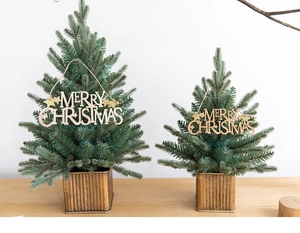 Close-up of decorative Christmas trees with golden wavy metal bases and Merry Christmas signs