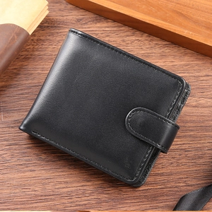 Detail of black PU leather men's wallet with snap button closure on a wooden table
