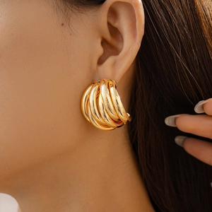 Close-up of gold multi-layered C-shaped earrings on model showing textured metallic finish