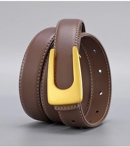 Close-up of vintage brown leather belt featuring a matte gold U-shaped buckle and stitching
