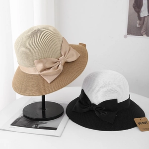 Detail of woven straw hats featuring satin bow decorations and UV protection tags