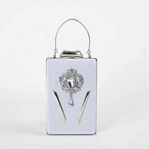 Detail van zilveren avondtas met kristallen hanger en metalen ringhandvat