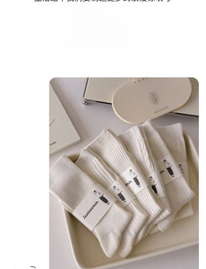 Detailed view of white knitted mid-calf socks with various textures on a ceramic plate