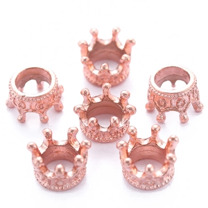Macro shot of rose gold crown alloy charms with intricate hollow carved patterns