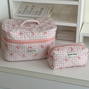Close-up of pink checkered quilted makeup bags featuring sweet bow patterns and handles