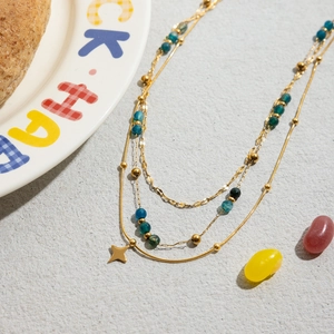 Détail du collier multicouche en acier doré 18K avec pierres bleues et étoile