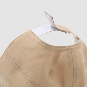 Vista macro di un cappellino in cotone beige con chiusura in velcro e cuciture precise