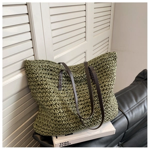 Detail of green woven straw tote bag texture and brown leather shoulder strap
