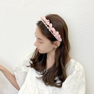 Close-up of pink satin headband with elegant pearl accents and ruffled fabric detail