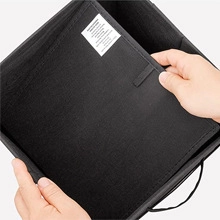 Detail showing hands inserting a stiff baseboard into a black foldable fabric storage bin