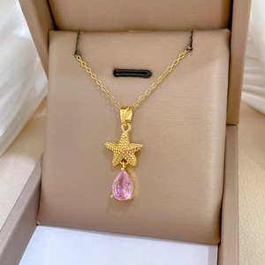 Macro shot of gold starfish pendant with pink teardrop crystal in a luxury jewelry box