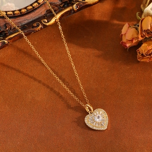 Gros plan du collier pendentif cœur doré avec des zircons brillants et détails floraux