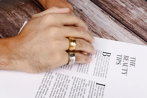 Detailed view of wide gold and silver stainless steel rings with a hammered texture finish