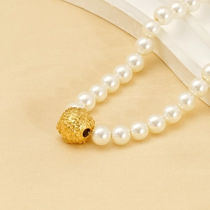 Close-up of pearl necklace with gold embossed floral bead on elegant textured background
