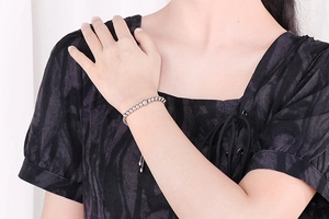 Detail showing polished silver beads on an adjustable bracelet worn on a female wrist