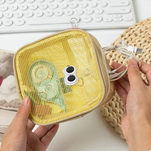 Macro shot of yellow mesh storage pouch with cartoon eyes for digital cables and tools