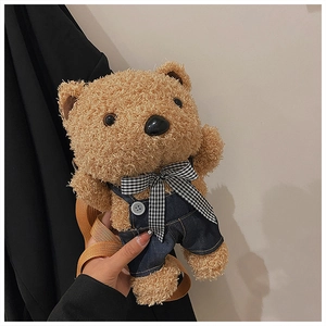 Close-up of cute plush teddy bear bag in denim overalls with a checkered bow tie