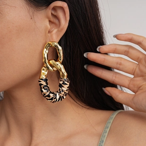 Close-up of model wearing gold geometric oval earrings with leopard print leather detail