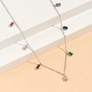 Detail of silver necklace with colorful square zircon pendants on modern geometric props